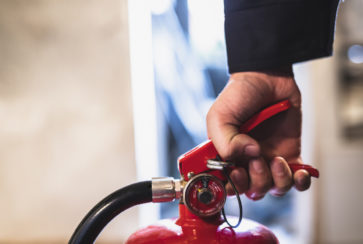 image of man checking a fire extinguisher Man haelt Feuerloescher