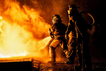 Two firefighters fighting a fire with a hose and water Two firefighters fighting a fire with a hose and water