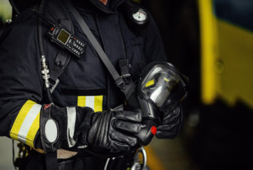 Rescue firefighter in safe helmet and uniform standing by car